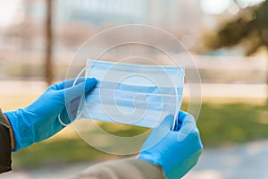 Women holds blue medical mask in medical gloves to stop from epidemy of coronavirus covid 19. Life after long quarantine