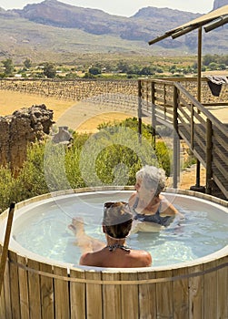 Women on holiday using a wood fired hot tub situated next to their tent