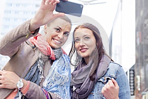 Women in jackets taking self portrait through mobile phone