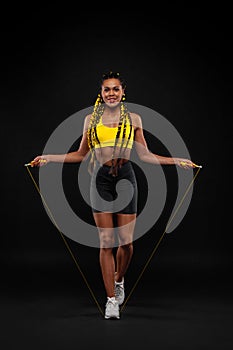 Women with jumping rope on black background. Beautiful young women standing with a jumping rope