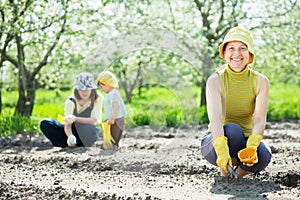 Women and kid sows seeds in soil