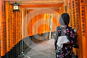 Women in kimono stand at Red Torii gates in Fushimi Inari shrine, Kyoto, Japan