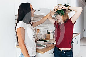 Women in the kitchen joke, laugh and have fun. Playing with vegetables