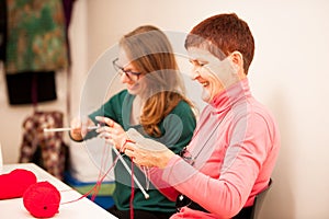 Women knitting with red wool. Eldery woman transfering her knowl