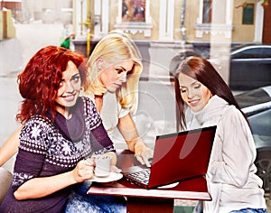 Women at laptop drinking coffee in a cafe.