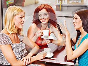 Women at laptop drinking coffee in a cafe.