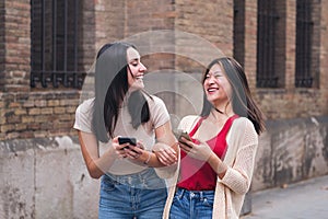 women laughing amused with cell phones in hand