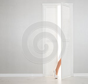 Women leg in white shoe looks out of the open door