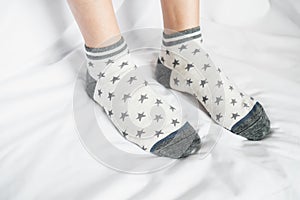 Women legs in socks colors alternating, side stand on white fabric floor.