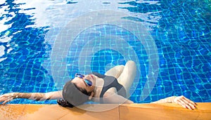 Women lifestyle relaxing near luxury swimming pool sunbath, summer day at the beach resort in the hotel.