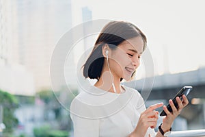 Women are listening to music from white headphones. And using hands touch to use various functions, happy mood.