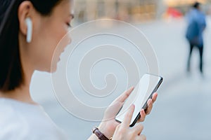 Women are listening to music from white headphones. And using hands touch to use various functions, happy mood.