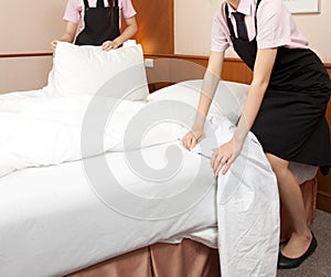 Women maid making bed in hotel room