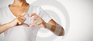 Women making heart shape with their fingers around pink ribbon