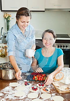 Women making sweet vareniki with berries