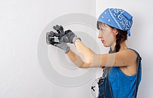 Women in the male profession: A girl repairs an electrical switch with a screwdriver and pliers.