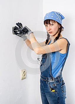 Women in the male profession: A girl repairs an electrical switch with a screwdriver and pliers.