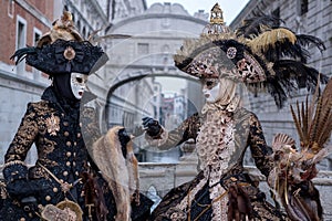 Women in masks and costumes with Bridge of Sighs behind, at Venice Carnival