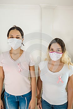 Women with masks and pink ribbons for the campaign against breast cancer on a white background