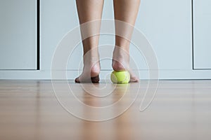 Woman massage with tennis ball to her foot in bedroom,Feet soles massage for plantar fasciitis photo