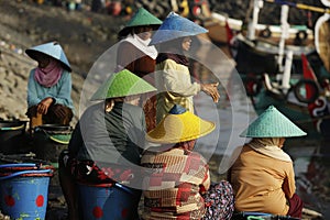 Women and men standing and waiting for the fishing boats