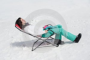 Women at mountains in winter lies on sun-lounger