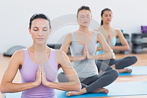 Women in Namaste position with eyes closed at fitness studio