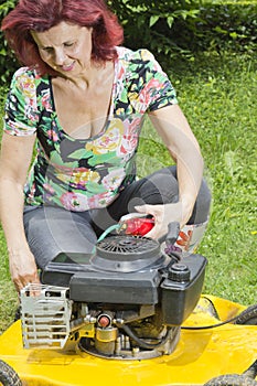 Women oiling yellow lawn mover