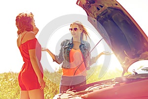 Women with open hood of broken car at countryside