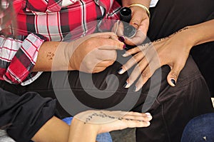 Women painting hands with henna