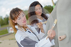 Women painting outdoor equipment