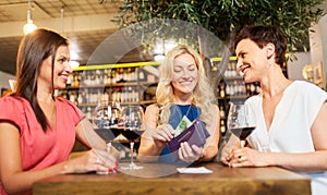 Women paying bill at wine bar or restaurant