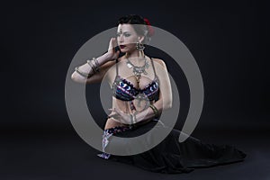 Women performs belly dance in ethnic dress on black background