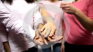 Women in pink shirts putting hands together, support, gender equality, feminism