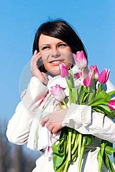 Women with pink tulips talking by a cellular