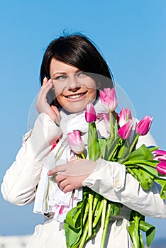 Women with pink tulips talking by a cellular