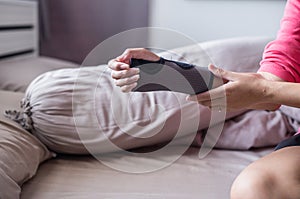 Women play mobile while elastic wrist support on hand to relieve pain