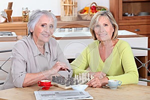 Women playing chess in kitchen