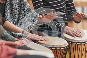 Women playing on the djembe drums during music therapy, drumming healing