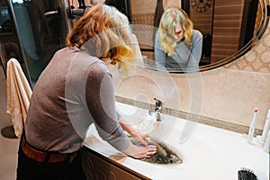 women with plunger and dirty sink with the clog in the pipe.