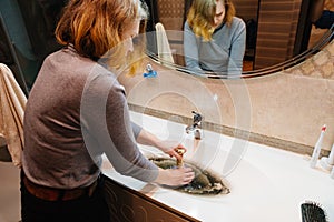 women with plunger and dirty sink with the clog in the pipe.