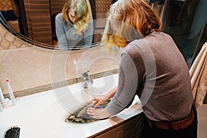 women with plunger and dirty sink with the clog in the pipe.