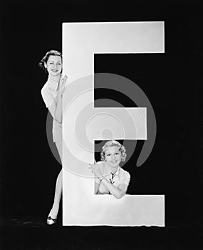 Women posing with huge letter E