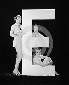 Women posing with huge letter E