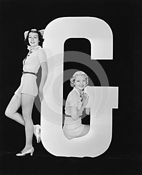 Women posing with huge letter G