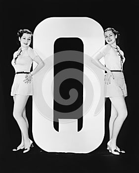 Women posing with huge letter Q