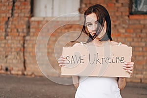 Women with Poster Save Ukraine. A woman with a belligerent look looks into the Camera