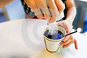 Women pouring sugar granules from sachet into black coffee