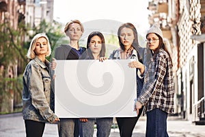 Women power. Group of young female activists are holding blank signboard while standing on the road during a women's