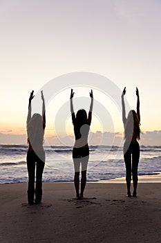 Women Practice Yoga on Beach At Sunrise or Sunset